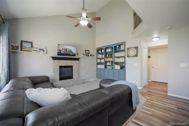 living area featuring light wood finished floors, a brick fireplace, baseboards, high vaulted ceiling, and a ceiling fan