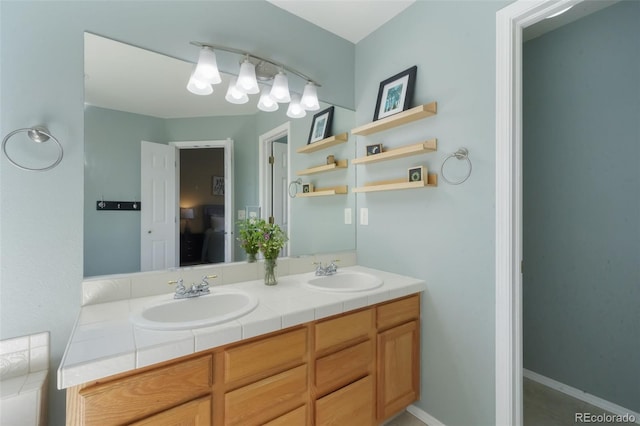 full bath featuring double vanity, baseboards, and a sink