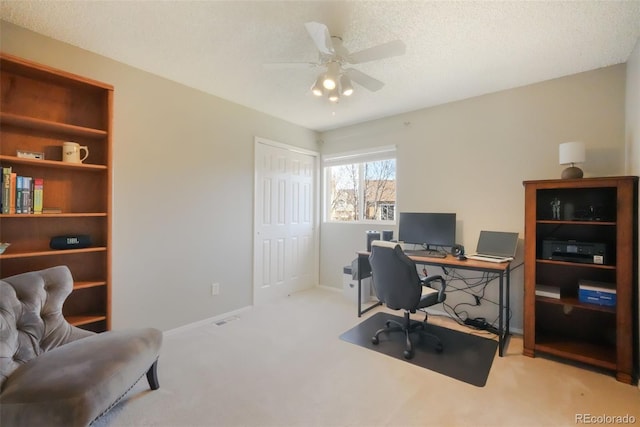 carpeted home office with visible vents, baseboards, a textured ceiling, and a ceiling fan