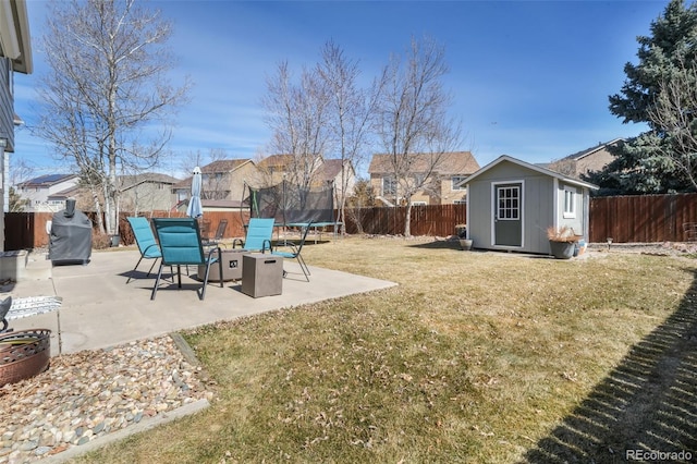 view of yard with an outbuilding, a fenced backyard, a patio, and a trampoline