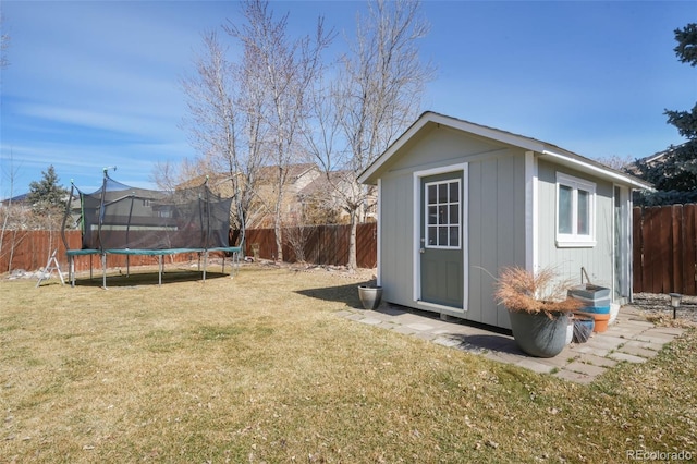 view of outdoor structure with an outbuilding, a fenced backyard, and a trampoline