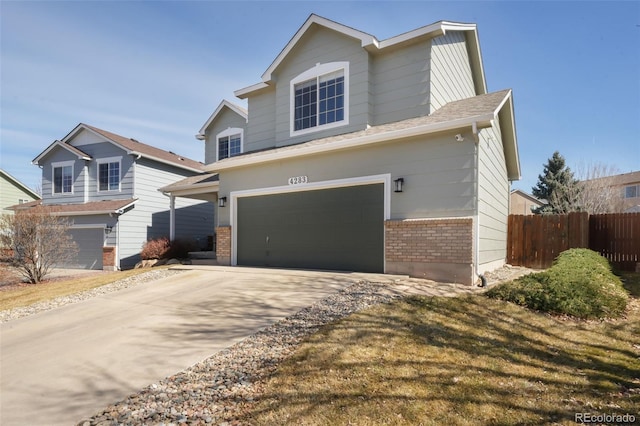 traditional home with brick siding, driveway, a garage, and fence