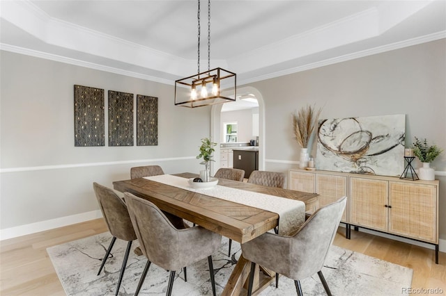 1311 Fletcher Dr, Erie, CO 80516 - dining area with a tray ceiling, light wood finished floors, crown molding, and arched walkways