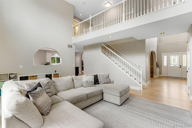 1311 Fletcher Dr, Erie, CO 80516 - living area with arched walkways, a towering ceiling, wood finished floors, stairway, and baseboards