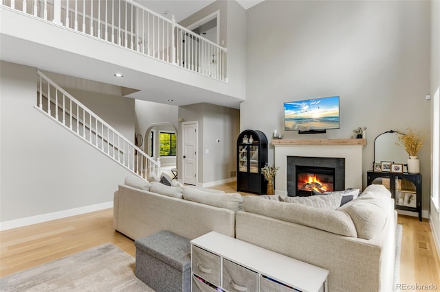 1311 Fletcher Dr, Erie, CO 80516 - living area featuring a high ceiling, wood finished floors, a glass covered fireplace, arched walkways, and baseboards