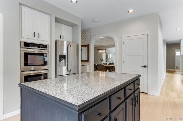 1311 Fletcher Dr, Erie, CO 80516 - kitchen featuring appliances with stainless steel finishes, arched walkways, white cabinetry, light wood-style flooring, and recessed lighting
