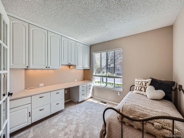 bedroom with light colored carpet, a textured ceiling, and baseboards