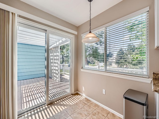 unfurnished dining area with light tile patterned flooring and baseboards