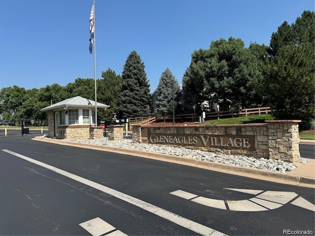 view of asphalt road with a gated entry and curbs