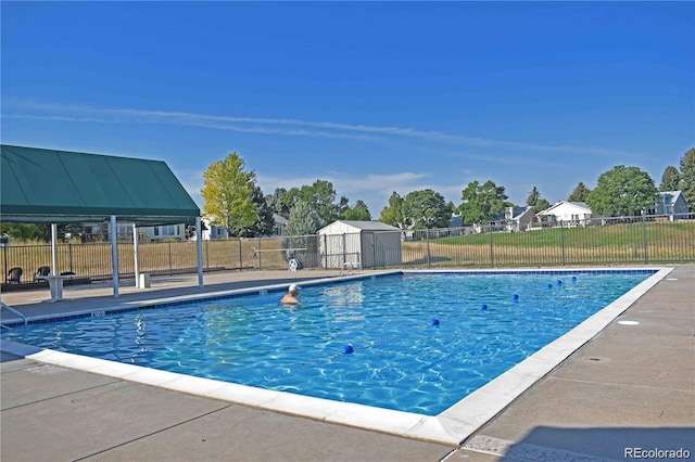 community pool with fence, a storage shed, and an outbuilding