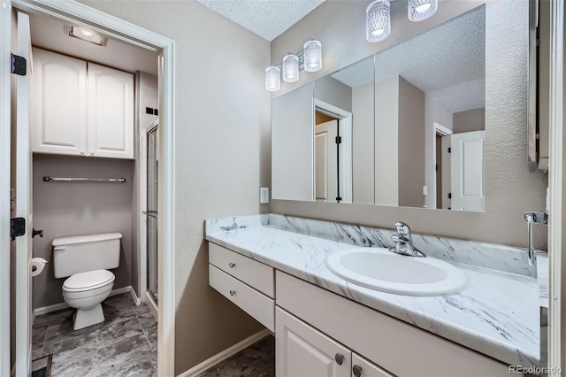 bathroom with toilet, a textured ceiling, a stall shower, vanity, and baseboards