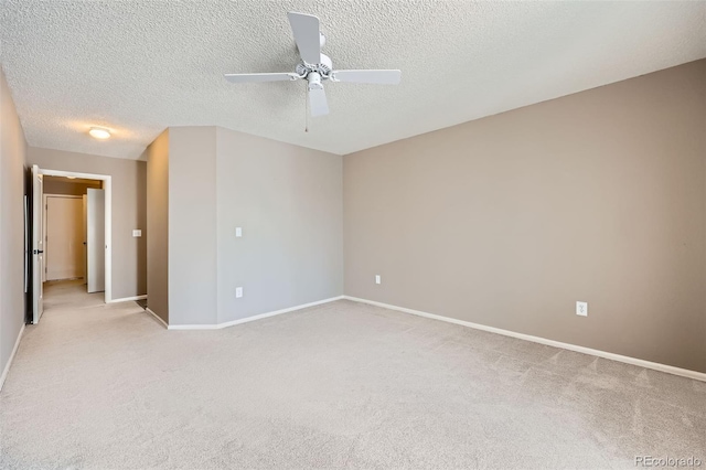spare room featuring a ceiling fan, light colored carpet, a textured ceiling, and baseboards