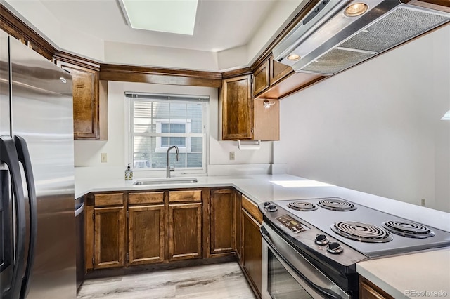 kitchen with appliances with stainless steel finishes, extractor fan, a sink, light countertops, and light wood-style floors