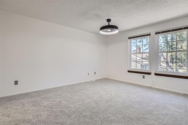 carpeted empty room with plenty of natural light, a textured ceiling, and baseboards