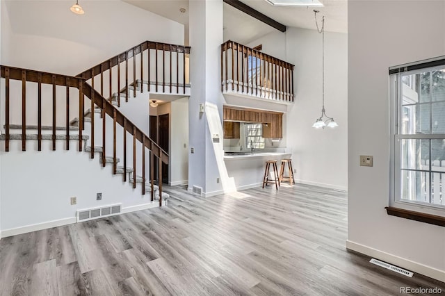 unfurnished living room with high vaulted ceiling, wood finished floors, stairway, baseboards, and beamed ceiling