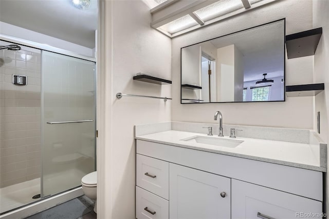 full bath featuring toilet, a stall shower, and vanity