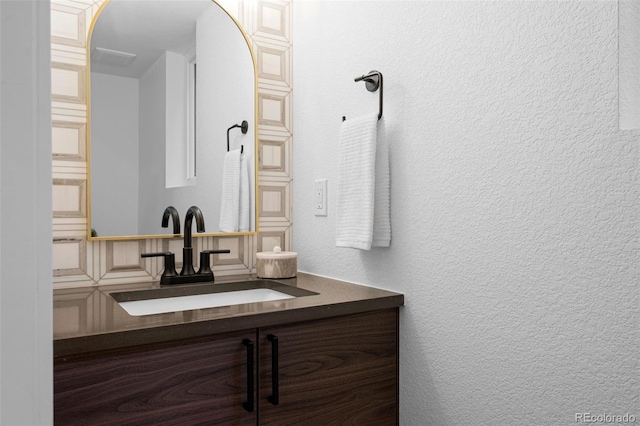 bathroom with a textured wall and vanity