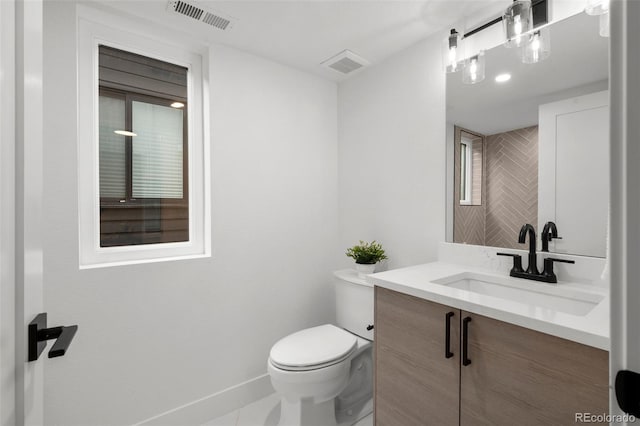bathroom featuring toilet, vanity, and baseboards