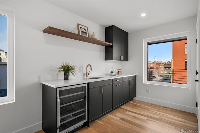 indoor wet bar with wine cooler, baseboards, light wood-style flooring, and recessed lighting