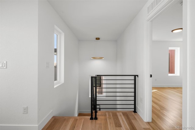 stairs featuring wood finished floors, healthy amount of natural light, and baseboards