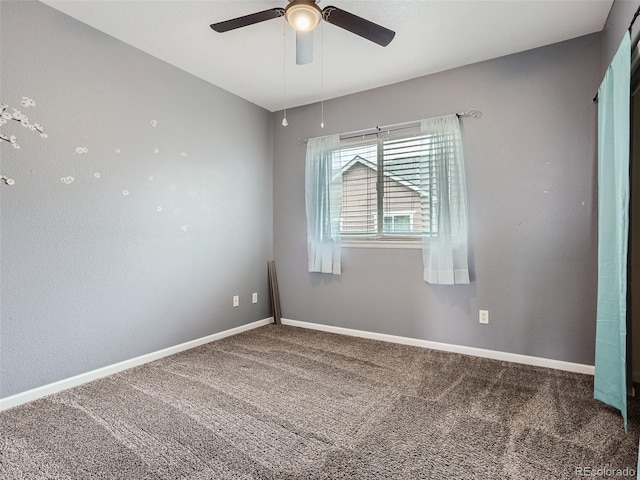 spare room featuring ceiling fan and dark colored carpet