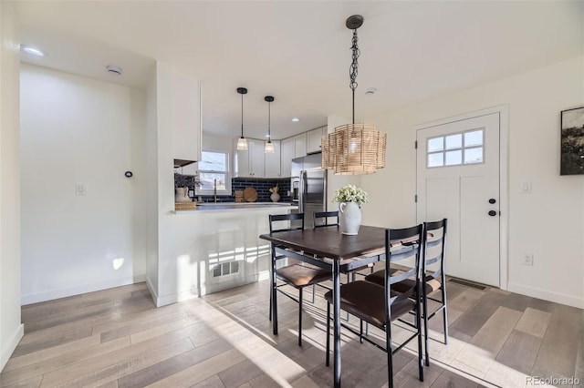 dining room featuring visible vents, light wood-style floors, baseboards, and a healthy amount of sunlight