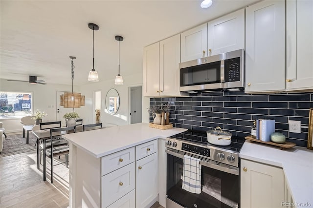 kitchen with white cabinets, backsplash, stainless steel appliances, and a peninsula