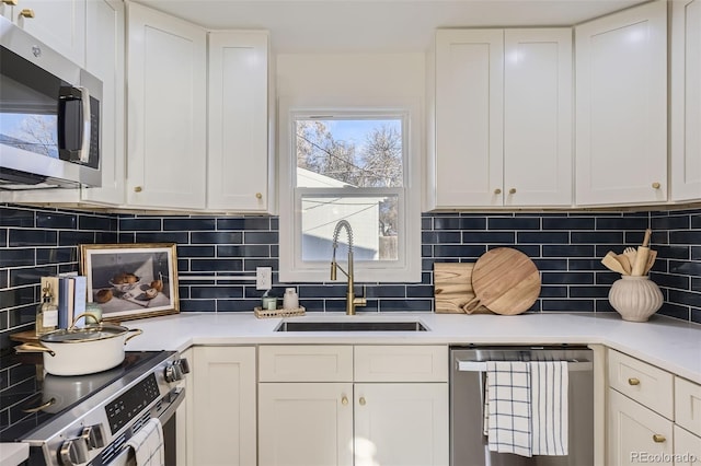 kitchen featuring a sink, white cabinetry, decorative backsplash, and stainless steel appliances