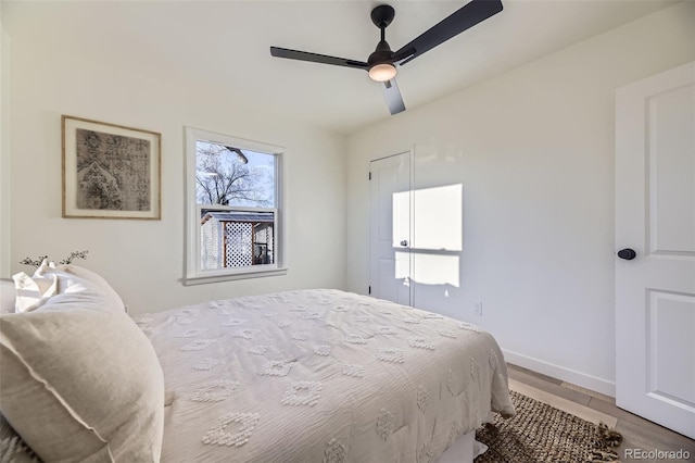 bedroom featuring baseboards, a ceiling fan, and light wood-style flooring