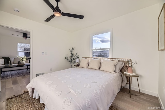bedroom with visible vents, a ceiling fan, baseboards, and wood finished floors