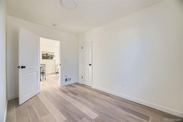 empty room featuring baseboards, light wood-style flooring, and visible vents