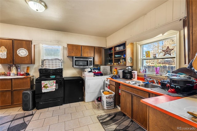 1437 Cypress St, Pueblo, CO 81004 - kitchen with electric range, stainless steel microwave, washer / clothes dryer, light tile patterned flooring, and brown cabinetry