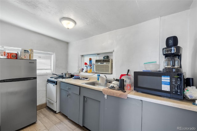 1437 Cypress St, Pueblo, CO 81004 - kitchen with freestanding refrigerator, black microwave, gas range gas stove, gray cabinets, and a sink