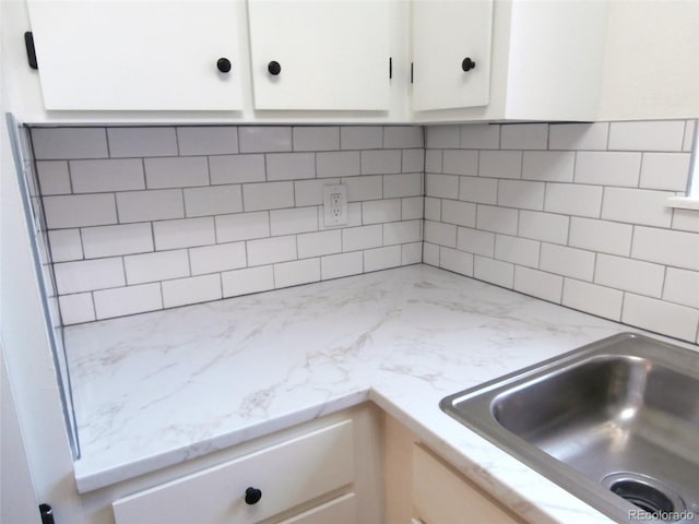 2215 S Buckley Rd Unit 201, Aurora, CO 80013 - kitchen view of white cabinetry, tasteful backsplash, light stone counters, and a sink
