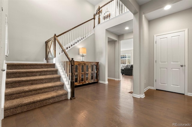 stairs with visible vents, wood finished floors, recessed lighting, a high ceiling, and baseboards