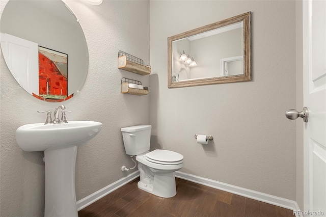 half bath featuring toilet, wood finished floors, and baseboards