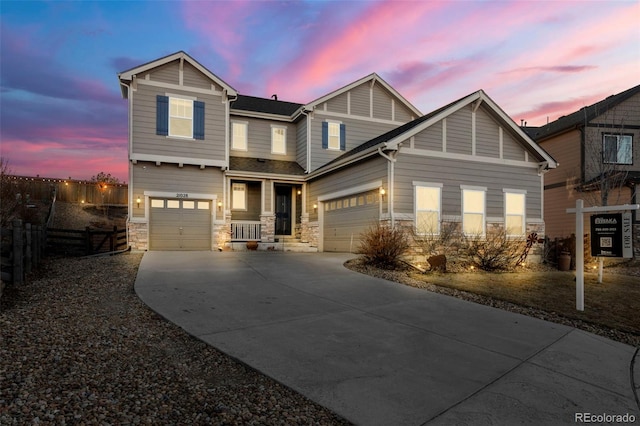 craftsman-style house featuring fence, stone siding, and driveway