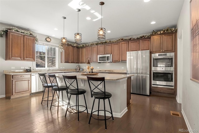 kitchen with visible vents, a breakfast bar, a kitchen island, dark wood finished floors, and appliances with stainless steel finishes