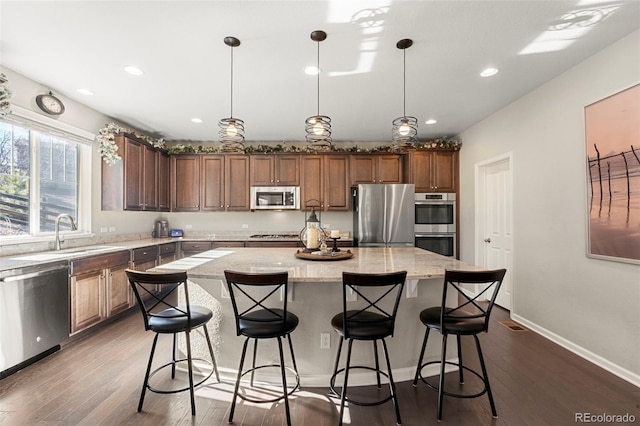 kitchen featuring a sink, light stone counters, dark wood-style floors, a center island, and stainless steel appliances