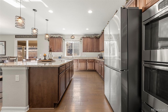 kitchen with pendant lighting, hardwood / wood-style flooring, a kitchen island, recessed lighting, and appliances with stainless steel finishes