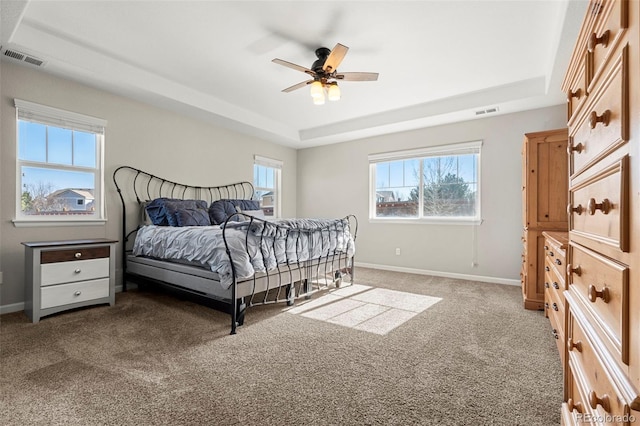 bedroom with a raised ceiling, carpet, visible vents, and baseboards