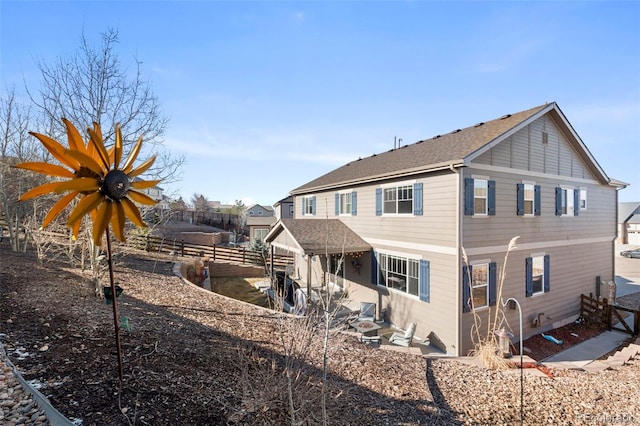 back of property featuring a patio area, a shingled roof, and fence