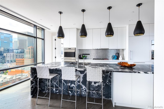 kitchen with wood finished floors, gas stovetop, white cabinets, decorative backsplash, and modern cabinets