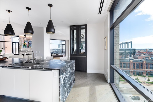 kitchen with hanging light fixtures, light wood-style floors, white cabinets, a sink, and modern cabinets