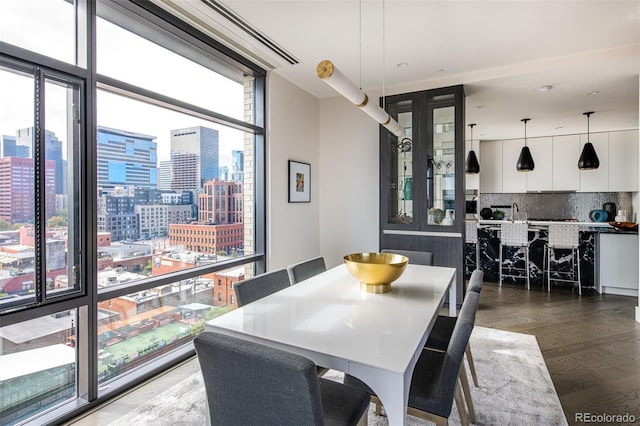 dining area featuring a wall of windows, a view of city, and wood finished floors