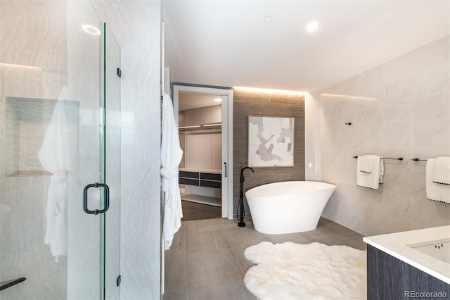 full bath with a soaking tub, tile patterned flooring, vanity, a shower stall, and tile walls