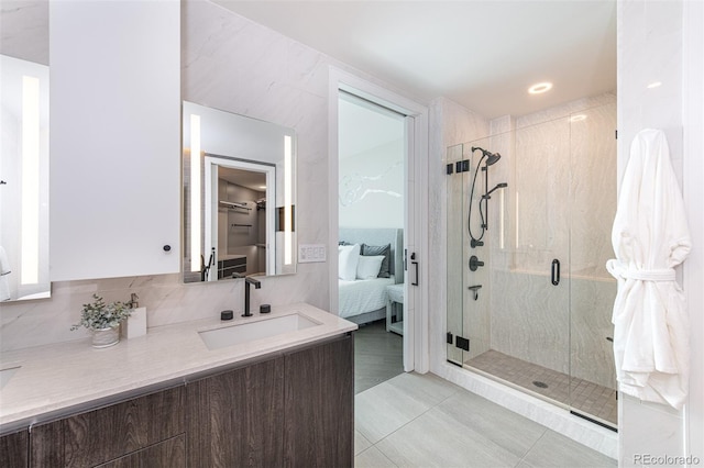 ensuite bathroom featuring a stall shower, connected bathroom, tile patterned flooring, vanity, and tile walls