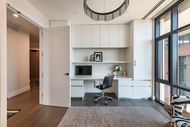 office featuring baseboards, visible vents, dark wood-type flooring, and built in study area