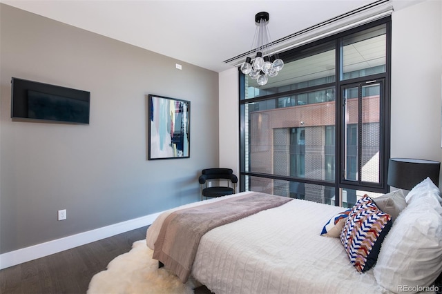 bedroom with an inviting chandelier, wood finished floors, and baseboards