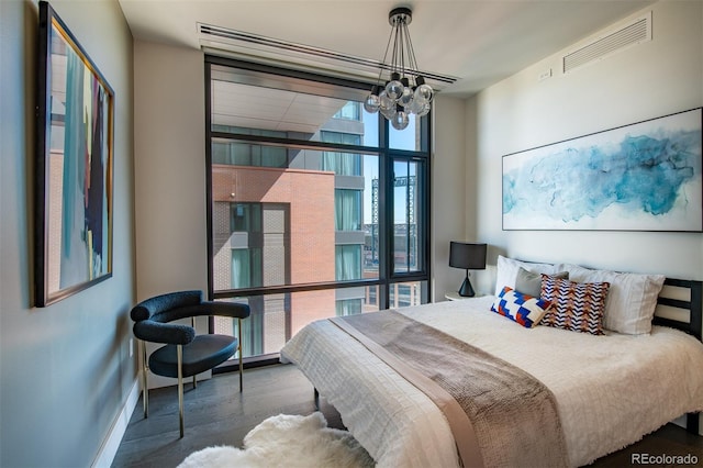 bedroom with wood finished floors, visible vents, baseboards, and an inviting chandelier